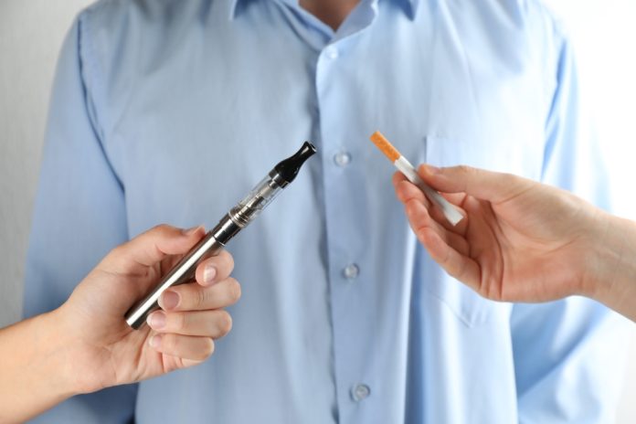 Man,Choosing,Between,Cigarette,And,Vaping,Device,On,Light,Background,